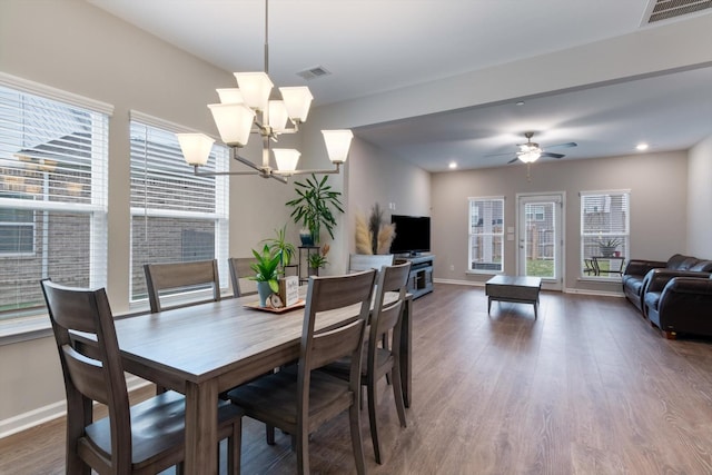 dining space with dark wood-type flooring and ceiling fan with notable chandelier