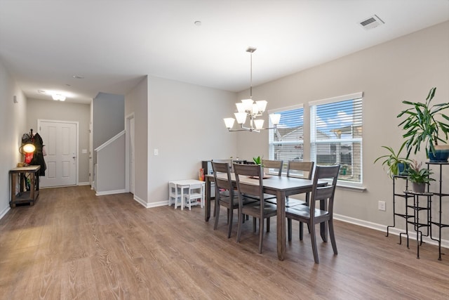 dining area with wood-type flooring and a chandelier