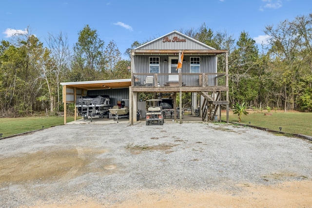 raised beach house with a front yard, a carport, and covered porch