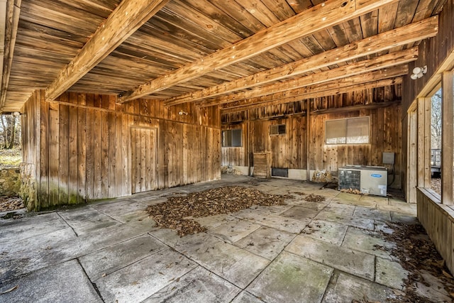 miscellaneous room with beamed ceiling and wood walls