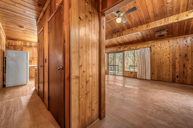 hall with wooden walls, wooden ceiling, and light hardwood / wood-style floors