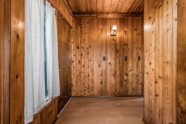 interior space with light wood-type flooring, wooden ceiling, and wood walls