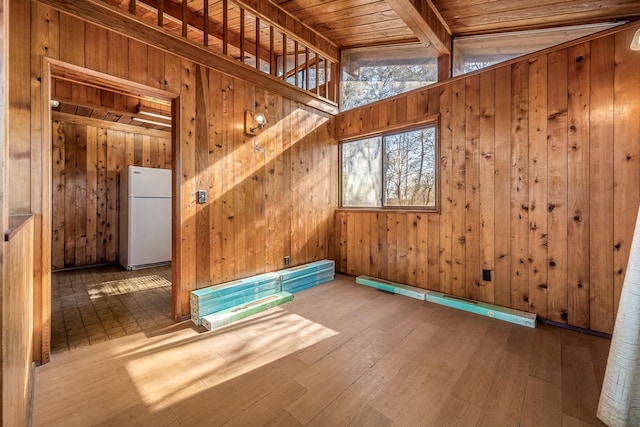 unfurnished room featuring lofted ceiling with beams, wood-type flooring, wood ceiling, and wooden walls