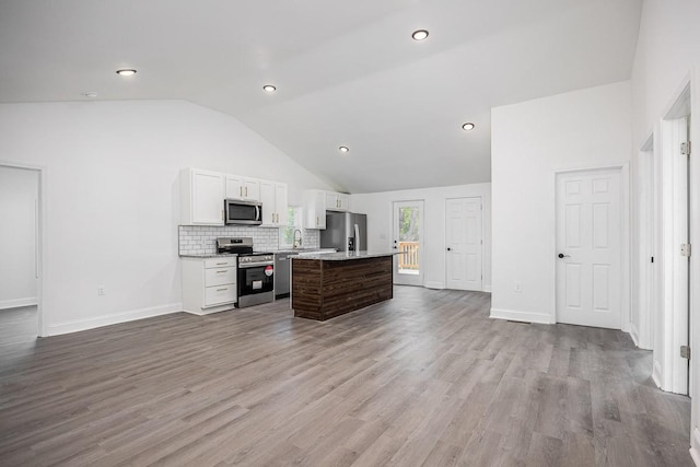 kitchen with lofted ceiling, sink, stainless steel appliances, white cabinets, and a kitchen island