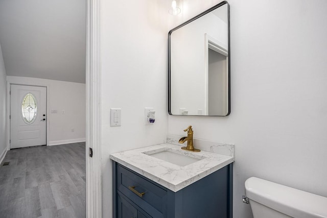 bathroom with hardwood / wood-style flooring, vanity, and toilet