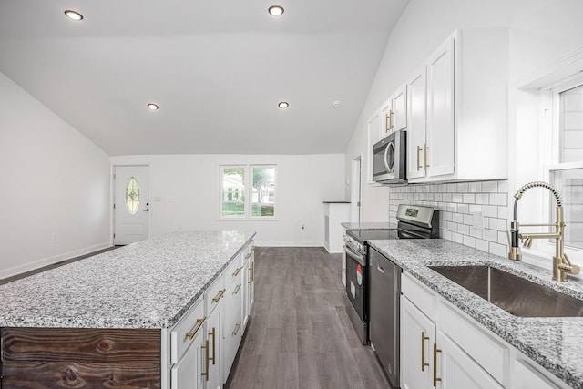 kitchen featuring lofted ceiling, sink, white cabinetry, stainless steel appliances, and light stone counters