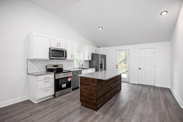 kitchen with sink, white cabinetry, a kitchen island, stainless steel appliances, and light stone countertops