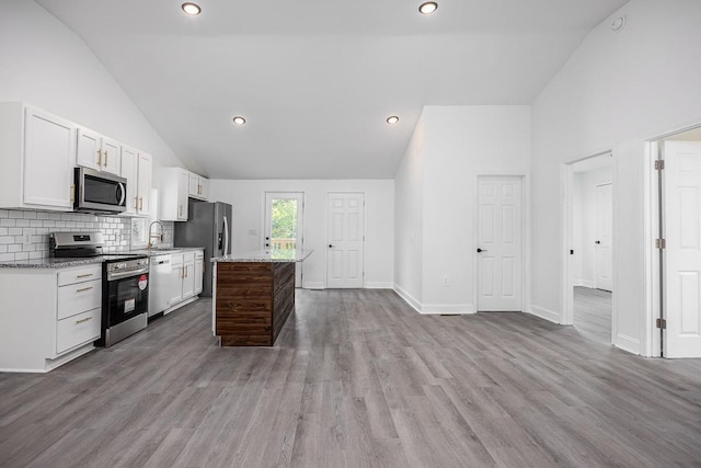 kitchen featuring light stone counters, a center island, light wood-type flooring, appliances with stainless steel finishes, and white cabinets