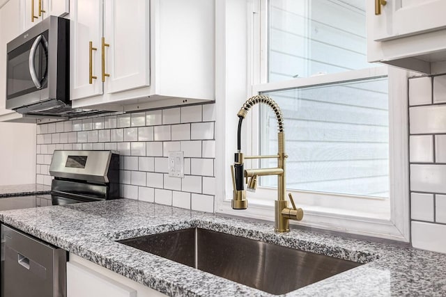 kitchen featuring sink, appliances with stainless steel finishes, light stone countertops, white cabinets, and decorative backsplash