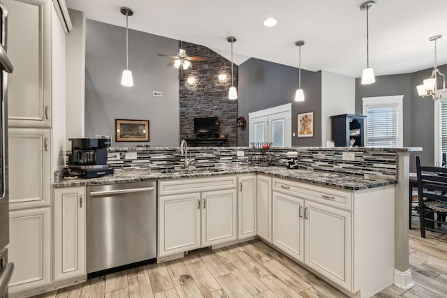 kitchen featuring pendant lighting, stainless steel dishwasher, dark stone counters, and kitchen peninsula