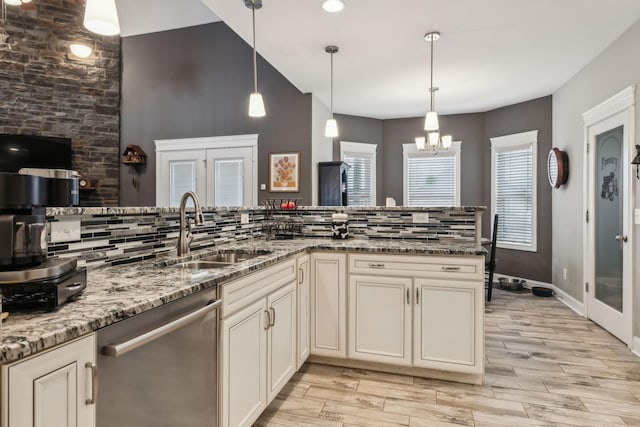 kitchen with sink, dishwasher, stone countertops, decorative light fixtures, and a chandelier