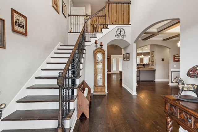 foyer entrance featuring coffered ceiling, a towering ceiling, dark hardwood / wood-style floors, and beamed ceiling