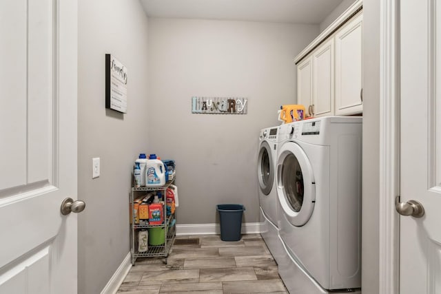 clothes washing area featuring cabinets, separate washer and dryer, and light wood-type flooring