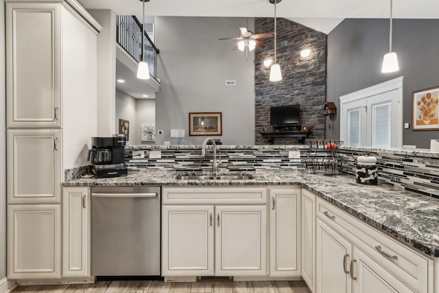 kitchen with sink, hanging light fixtures, dark stone countertops, stainless steel dishwasher, and ceiling fan