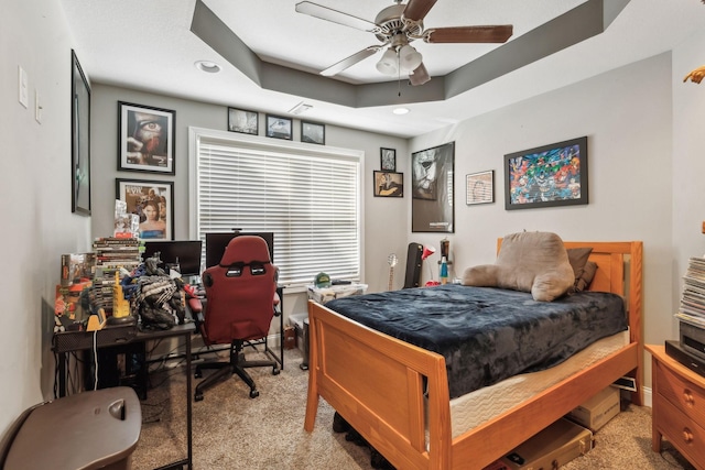 carpeted bedroom with a raised ceiling and ceiling fan