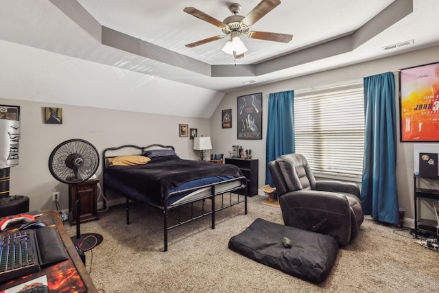 bedroom featuring ceiling fan, a tray ceiling, and carpet