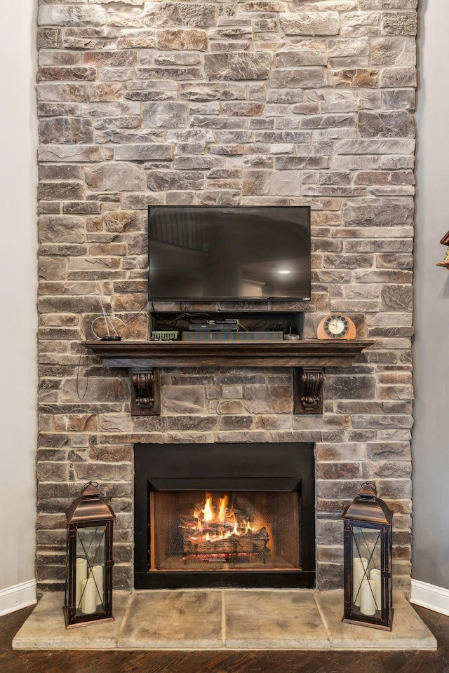 details with hardwood / wood-style flooring and a stone fireplace