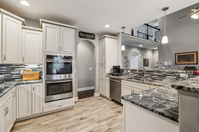 kitchen with appliances with stainless steel finishes, pendant lighting, sink, dark stone countertops, and decorative backsplash