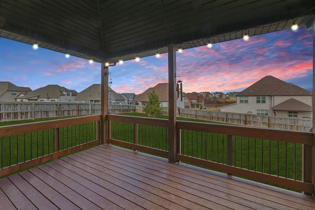 deck at dusk featuring a yard