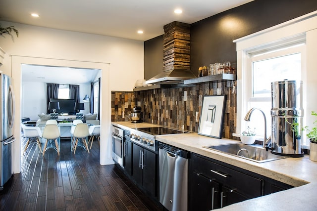 kitchen featuring appliances with stainless steel finishes, sink, backsplash, dark wood-type flooring, and custom range hood