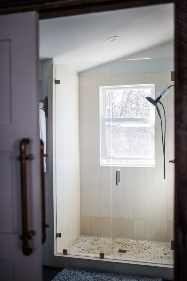 bathroom featuring vaulted ceiling and a shower with shower door