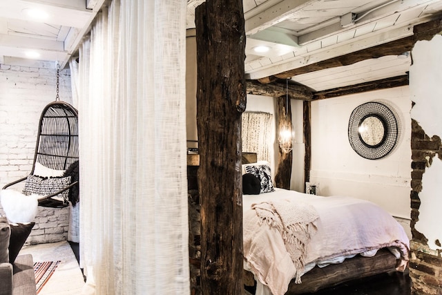 bedroom with beamed ceiling and brick wall