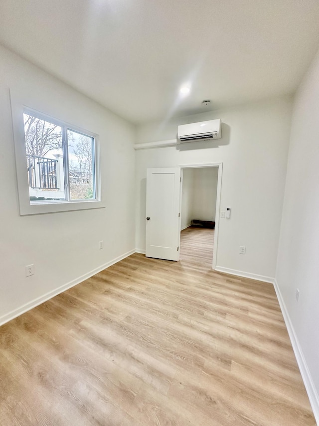 spare room featuring a wall mounted air conditioner and light hardwood / wood-style flooring