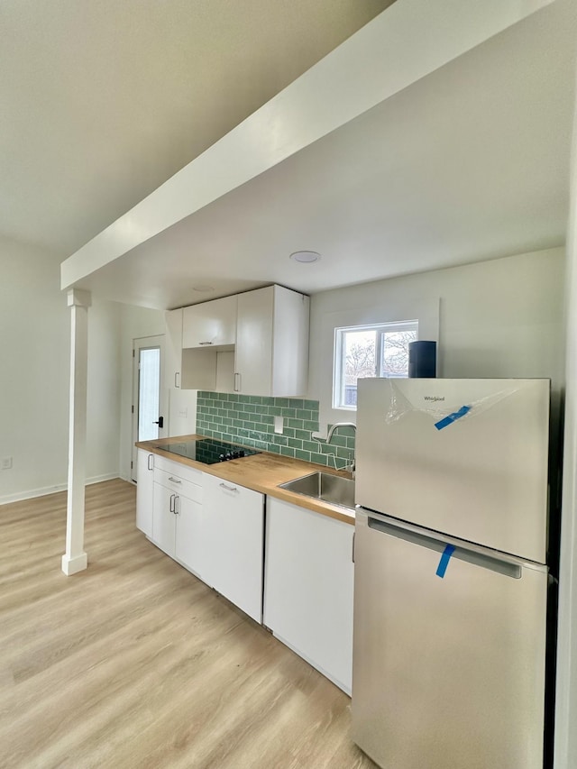 kitchen featuring wood counters, sink, white cabinetry, refrigerator, and light hardwood / wood-style floors