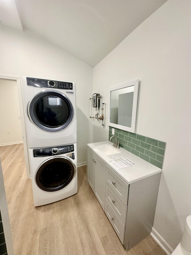 laundry room featuring sink, light hardwood / wood-style flooring, and stacked washing maching and dryer