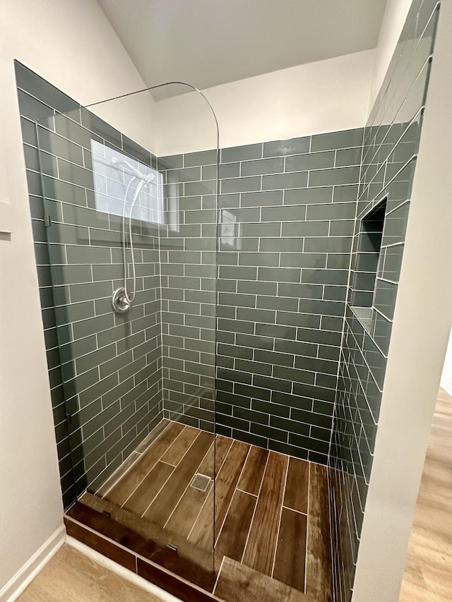 bathroom with hardwood / wood-style flooring and tiled shower