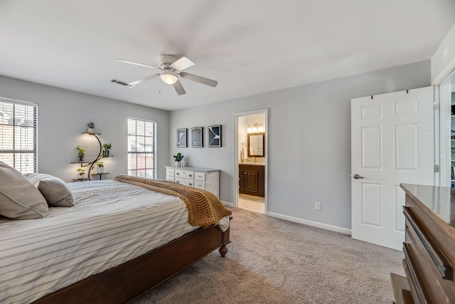 bedroom featuring ensuite bath, light colored carpet, and ceiling fan