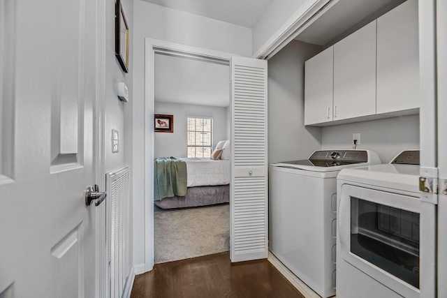 laundry room featuring washer and dryer, dark hardwood / wood-style flooring, and cabinets