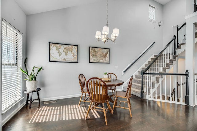 dining room featuring a towering ceiling, a wealth of natural light, and dark wood-type flooring