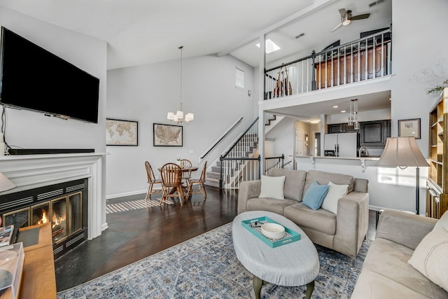 living room with dark wood-type flooring, beam ceiling, ceiling fan with notable chandelier, and high vaulted ceiling