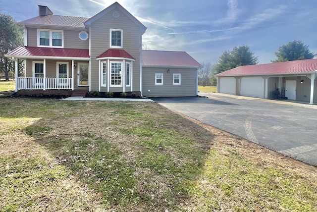 view of front of property with a garage, an outdoor structure, a porch, and a front yard