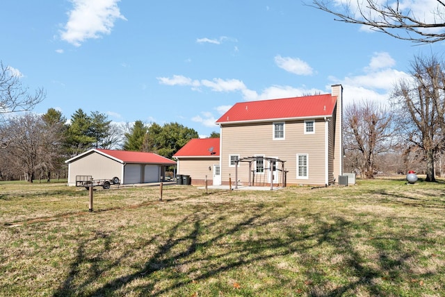 back of house featuring an outbuilding, a yard, a garage, and central air condition unit