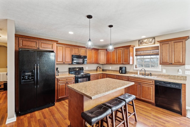 kitchen with light hardwood / wood-style floors, sink, black appliances, and a center island