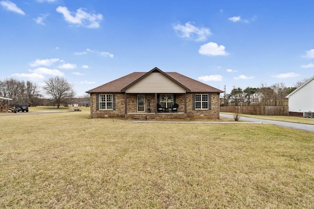 ranch-style home featuring cooling unit, covered porch, and a front yard