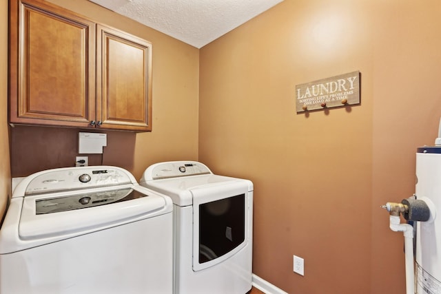 clothes washing area with cabinets, washer and dryer, and a textured ceiling