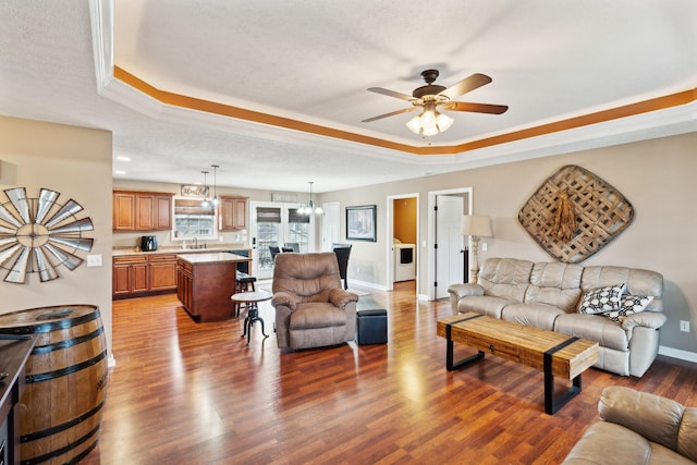 living room featuring sink, wood-type flooring, a raised ceiling, and a textured ceiling