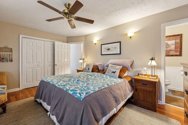 bedroom with hardwood / wood-style flooring, ceiling fan, connected bathroom, a textured ceiling, and a closet