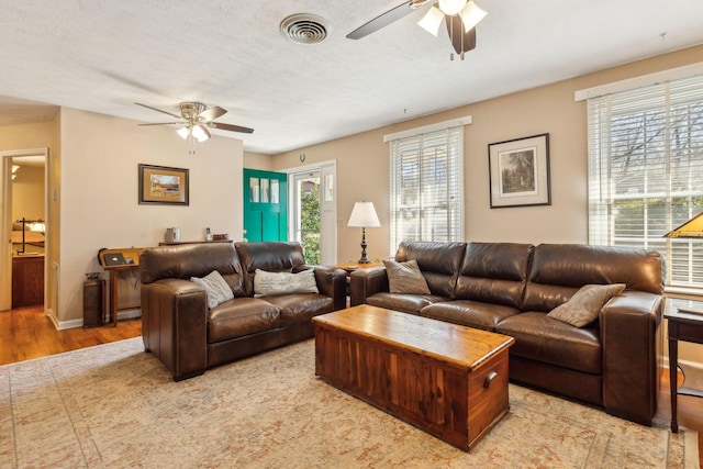 living room featuring a textured ceiling, ceiling fan, and light hardwood / wood-style flooring