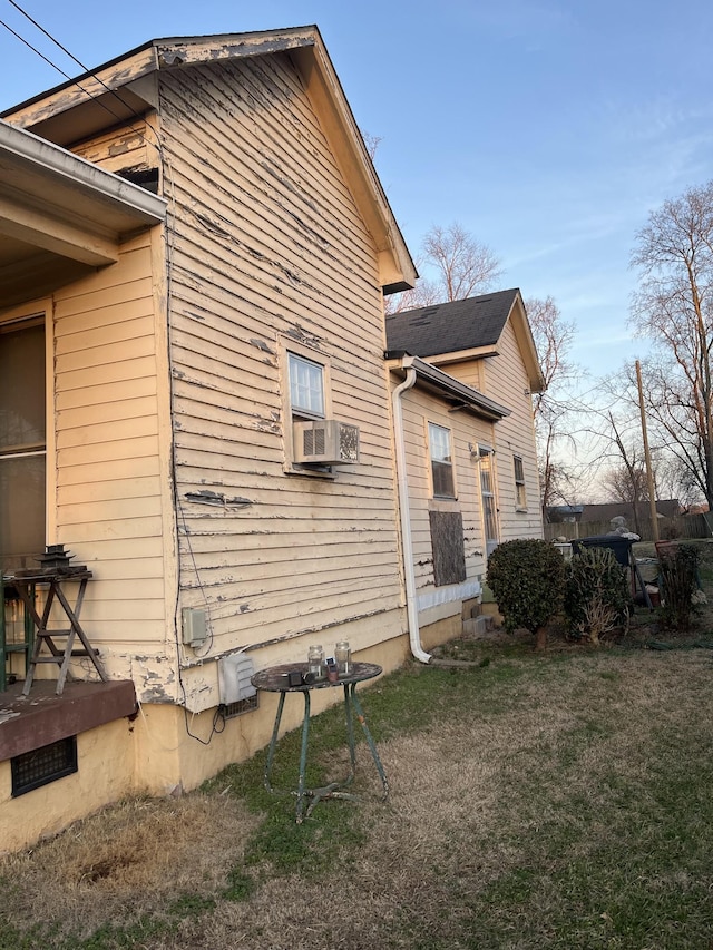 view of side of property featuring cooling unit and a lawn