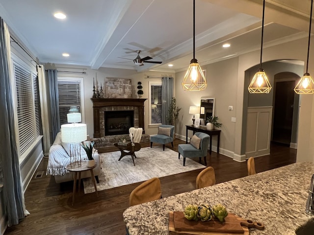 living room with crown molding, beam ceiling, dark wood-type flooring, and ceiling fan