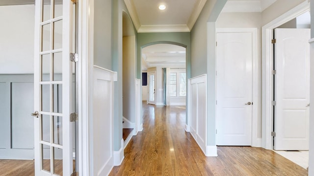 hall with ornamental molding and light hardwood / wood-style floors