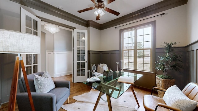 living area with ornamental molding, wood-type flooring, ceiling fan with notable chandelier, and french doors