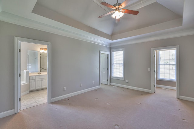 spare room featuring a tray ceiling, ornamental molding, light colored carpet, and ceiling fan