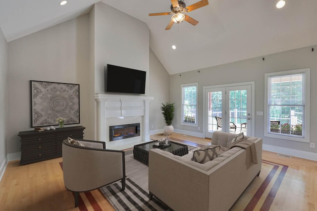 living room featuring ceiling fan, high vaulted ceiling, and light wood-type flooring