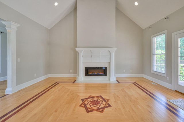 unfurnished living room with high vaulted ceiling and ornate columns