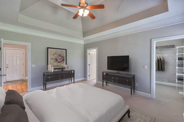 bedroom with a tray ceiling, ornamental molding, and a spacious closet